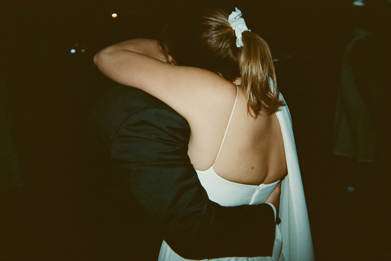 Two people holding each other in the middle of a standing crowd.